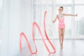 Beautiful little gymnast girl in pink sportswear dress, doing rhythmic gymnastics exercise Spirals with art ribbon Royalty Free Stock Photo