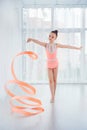 Beautiful little gymnast girl in pink sportswear dress, doing rhythmic gymnastics exercise Spirals with art ribbon Royalty Free Stock Photo