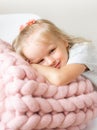 Beautiful Little Happy Blond Ginger Girl Sitting on Bed with a Pink Merino Woolen Blanket Royalty Free Stock Photo