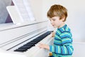 Beautiful little kid boy with headphones playing piano in living room or music school. Preschool child having fun with Royalty Free Stock Photo