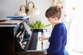 Beautiful little kid boy playing piano in living room. Child having fun with learning to play music instrument with Royalty Free Stock Photo