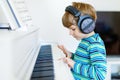 Beautiful little kid boy playing piano in living room or music school Royalty Free Stock Photo