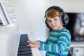 Beautiful little kid boy playing piano in living room or music school Royalty Free Stock Photo