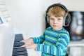 Beautiful little kid boy playing piano in living room or music school Royalty Free Stock Photo