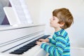 Beautiful little kid boy playing piano in living room or music school Royalty Free Stock Photo