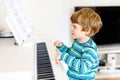 Beautiful little kid boy playing piano in living room or music school Royalty Free Stock Photo