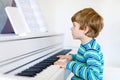 Beautiful little kid boy playing piano in living room or music school Royalty Free Stock Photo