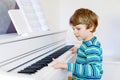 Beautiful little kid boy playing piano in living room or music school Royalty Free Stock Photo