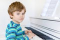 Beautiful little kid boy playing piano in living room or music school Royalty Free Stock Photo