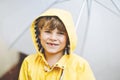 Beautiful little kid boy on way to school walking during sleet, heavy rain and snow with an umbrella on cold day. Happy Royalty Free Stock Photo
