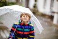 Beautiful little kid boy on way to school walking during sleet, rain and snow with an umbrella on cold day. Happy and Royalty Free Stock Photo