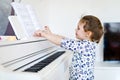 Beautiful little kid girl playing piano in living room or music school Royalty Free Stock Photo