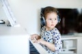 Beautiful little kid girl playing piano in living room or music school Royalty Free Stock Photo