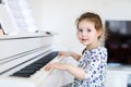 Beautiful little kid girl playing piano in living room or music school