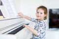 Beautiful little kid girl playing piano in living room or music school Royalty Free Stock Photo