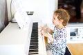 Beautiful little kid girl playing piano in living room or music school. Preschool child having fun with learning to play Royalty Free Stock Photo