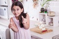 Beautiful little middle eastern 7 years old girl is working with knife and onion in the white kitchen. studio shot.