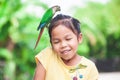 Beautiful parrot birds standing on child head. Asian child girl play with her pet parrot bird with fun