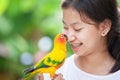 Little parrot birds standing on woman hand. Asian teenager girl play with her pet parrot bird with fun and love Royalty Free Stock Photo