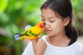 Beautiful parrot birds standing on woman hand. Asian teenager girl play with her pet parrot bird with fun and love Royalty Free Stock Photo