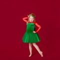 Beautiful little plump girl princess dancing in luxury green dress isolated on red background. Carnival party with costumes Royalty Free Stock Photo