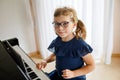 Beautiful little preschool girl playing piano at music school. Cute child having fun with learning to play music Royalty Free Stock Photo
