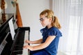 Beautiful little preschool girl playing piano at music school. Cute child having fun with learning to play music Royalty Free Stock Photo