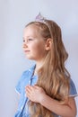 Beautiful little princess girl in silver crown holding magic wand smiling. Young lady with long wavy hair in blue dress Royalty Free Stock Photo