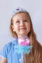 Beautiful little princess girl in silver crown holding magic wand smiling. Young lady with long wavy hair in blue dress Royalty Free Stock Photo