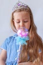 Beautiful little princess girl in silver crown holding magic wand smiling. Young lady with long wavy hair in blue dress Royalty Free Stock Photo