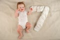 Beautiful little redhead baby in a white bodysuit on the bed close-up and copy space. Newborn by months and the number 7 from diap Royalty Free Stock Photo