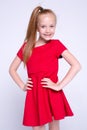 Beautiful little redhead girl in red dress posing like model on white background. Royalty Free Stock Photo