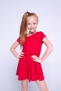 Beautiful little redhead girl in red dress posing like model on white background. Royalty Free Stock Photo