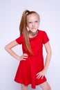 Beautiful little redhead girl in red dress posing like model on white background. Royalty Free Stock Photo