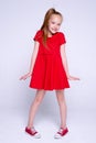 Beautiful little redhead girl in red dress and sneakers Royalty Free Stock Photo
