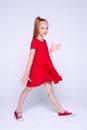 Beautiful little redhead girl in red dress and sneakers posing l Royalty Free Stock Photo