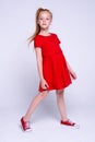 Beautiful little redhead girl in red dress and sneakers posing l Royalty Free Stock Photo