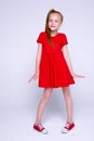 Beautiful little redhead girl in red dress and sneakers posing l Royalty Free Stock Photo