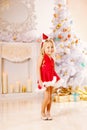 Beautiful little Santa girl near the Christmas tree. Happy girl Royalty Free Stock Photo