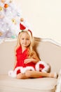 Beautiful little Santa girl near the Christmas tree. Happy girl Royalty Free Stock Photo
