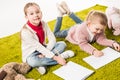 beautiful little sisters drawing together on floor