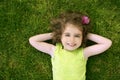 Beautiful little toddler girl happy lying on grass