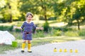 Beautiful little toddler girl playing in park. Adorable child wearing fashion casual clothes and yellow rubber boots. Royalty Free Stock Photo