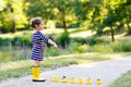 Beautiful little toddler girl playing in park. Adorable child wearing fashion casual clothes and yellow rubber boots. Royalty Free Stock Photo