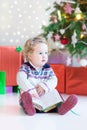 Beautiful little toddler girl reading a book sitting under a dec Royalty Free Stock Photo