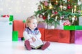 Beautiful little toddler girl reading a book under Christmas tree Royalty Free Stock Photo