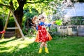 Beautiful little toddler girl in yellow rubber boots and colorful dress watering spring flowers with kids water can Royalty Free Stock Photo