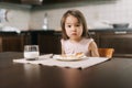 Beautiful little two-year-old girl is waiting for the meal to begin, looking at the camera.. Royalty Free Stock Photo