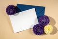 Beautiful little violet flowers on postal blue envelope on beige background, empty paper note copy space for text