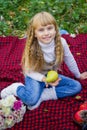 Beautiful little young baby in a pink hat with pear in hand. Beautiful child sitting on a red plaid.